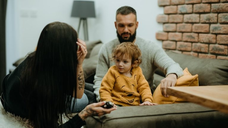 a man sitting on a couch next to a little girl