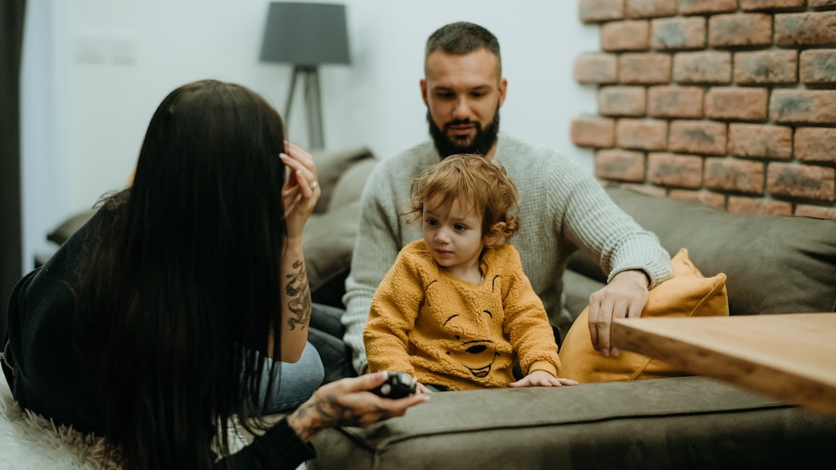 a man sitting on a couch next to a little girl